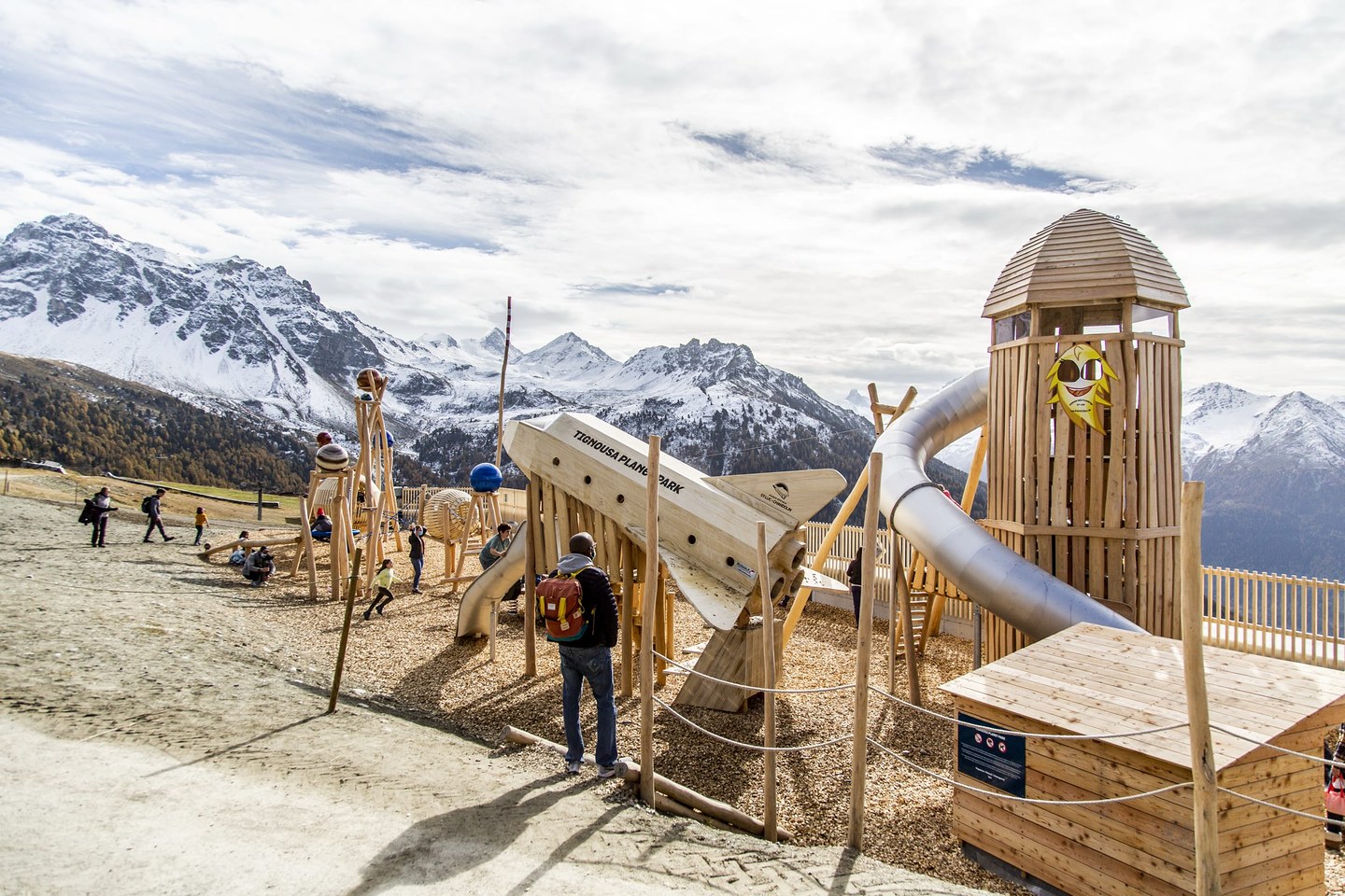 Le Planet Park de Tignousa : place de jeux en bois avec fusée et tour à toboggan, face aux sommets enneigés