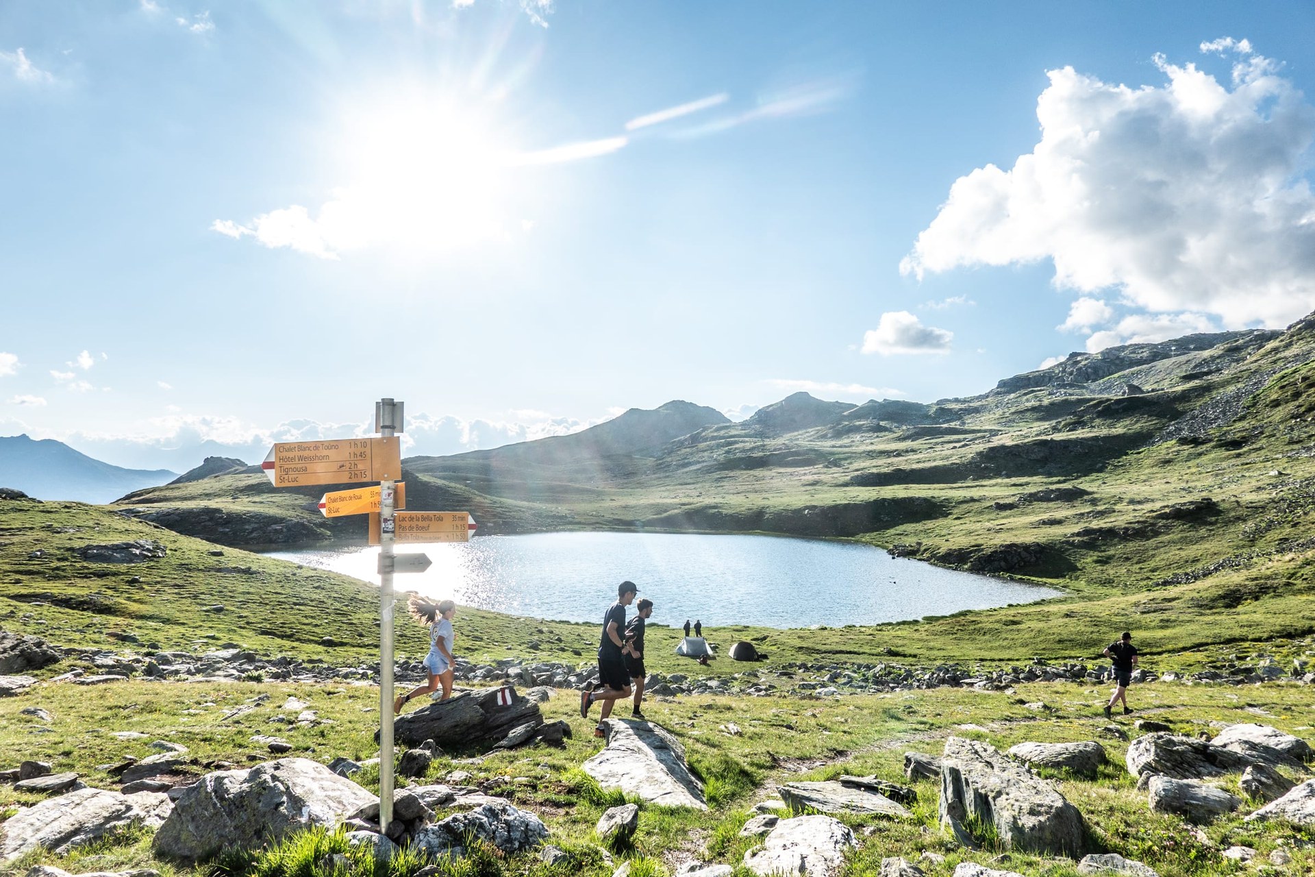 Des coureurs sur un sentier balisé longeant un lac d’altitude du domaine, en été
